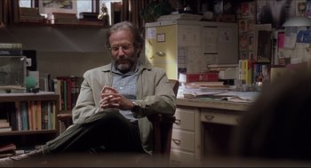 Movie still from “Good Will Hunting” (1997), directed by Gus Van Sant – A man sitting in a chair in front of a desk; Medium shot, Over the shoulder angle