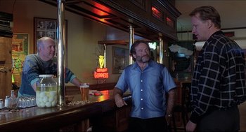 Movie still from “Good Will Hunting” (1997), directed by Gus Van Sant – A man standing at a bar holding a cell phone in his hand; Medium shot, Low angle