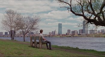 Movie still from “Good Will Hunting” (1997), directed by Gus Van Sant – A man sitting on top of a wooden park bench; Extreme Wide shot, Over the shoulder angle