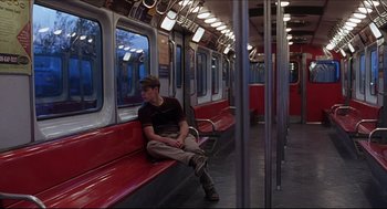 Movie still from “Good Will Hunting” (1997), directed by Gus Van Sant – A man sitting on a red bench on a train; Wide shot, Low angle