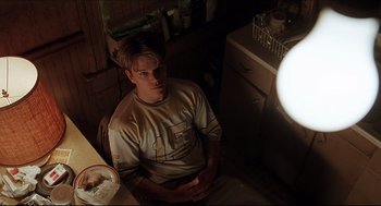 Movie still from “Good Will Hunting” (1997), directed by Gus Van Sant – A man sitting in a chair in a kitchen; Medium shot, Low angle