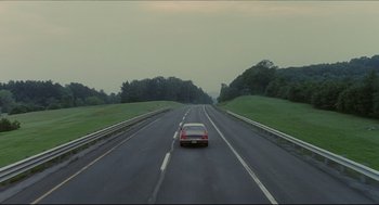 Movie still from “Good Will Hunting” (1997), directed by Gus Van Sant – A car driving down a road near a lush green field; Extreme Wide shot, High angle
