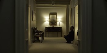 Movie still from “House of Cards” (2013), created by Beau Willimon – A man in a suit sitting in a hallway; Wide shot, Low angle