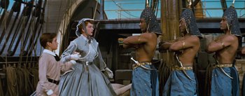 Movie still from “The King and I” (1956), directed by Walter Lang – A man and a woman standing next to each other on a boat; Medium shot, High angle