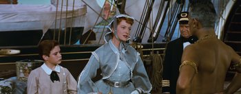 Movie still from “The King and I” (1956), directed by Walter Lang – A woman in a blue dress and a white hat; Medium shot, Low angle