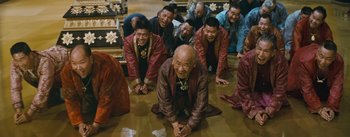 Movie still from “The King and I” (1956), directed by Walter Lang – A group of men in traditional garb kneeling on the ground; Wide shot, High angle