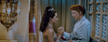 Movie still from “The King and I” (1956), directed by Walter Lang – A woman holding a man's hand while wearing a tiara; Medium shot, High angle
