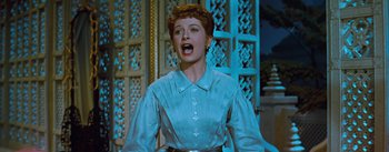 Movie still from “The King and I” (1956), directed by Walter Lang – A woman in a white shirt is singing; Medium shot, Low angle