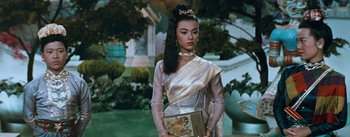 Movie still from “The King and I” (1956), directed by Walter Lang – A woman in a silver dress holding a purse; Medium shot, Low angle