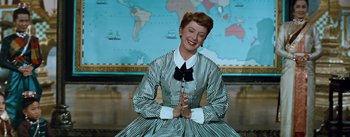 Movie still from “The King and I” (1956), directed by Walter Lang – A woman sitting in front of a map of the world; Medium shot, High angle