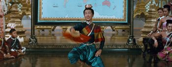 Movie still from “The King and I” (1956), directed by Walter Lang – A woman in traditional dress dancing in front of a map; Medium shot, High angle