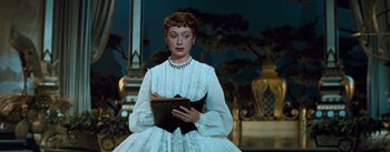 Movie still from “The King and I” (1956), directed by Walter Lang – A woman in a white dress holding a book in her hands; Medium shot, Low angle