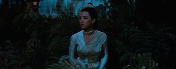 Movie still from “The King and I” (1956), directed by Walter Lang – A woman wearing a tiara and a white dress in a forest; Medium shot, Over the shoulder angle