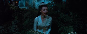 Movie still from “The King and I” (1956), directed by Walter Lang – A woman in a white dress standing next to a tree; Medium shot, High angle