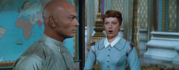 Movie still from “The King and I” (1956), directed by Walter Lang – A woman in a blue dress and a bald man; Medium shot, Low angle