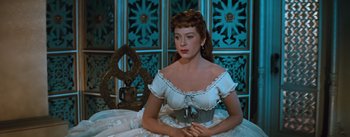 Movie still from “The King and I” (1956), directed by Walter Lang – A woman in a white dress sitting in front of a blue wall; Medium shot, Low angle