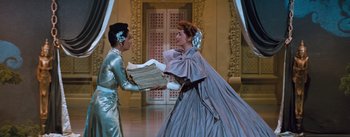 Movie still from “The King and I” (1956), directed by Walter Lang – Two people in a costume are holding papers in a room; Medium shot, Low angle