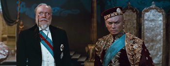 Movie still from “The King and I” (1956), directed by Walter Lang – A man in a suit standing next to another man in a suit; Medium shot, Over the shoulder angle
