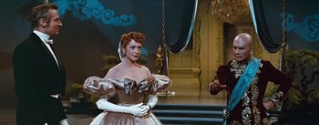 Movie still from “The King and I” (1956), directed by Walter Lang – A woman in a dress and gloves standing in front of a man; Medium shot, Low angle