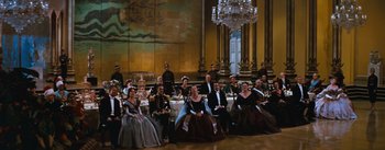 Movie still from “The King and I” (1956), directed by Walter Lang – A group of people sitting at a table in formal wear; Wide shot, High angle