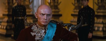 Movie still from “The King and I” (1956), directed by Walter Lang – A man with bald head wearing a blue sash; Close Up shot, Low angle