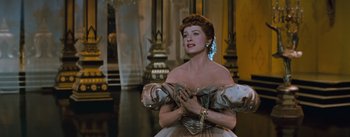 Movie still from “The King and I” (1956), directed by Walter Lang – A beautiful woman in a dress standing in front of a mirror; Medium shot, Low angle