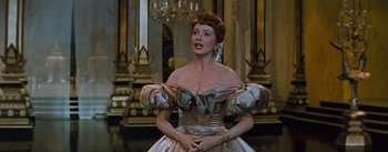 Movie still from “The King and I” (1956), directed by Walter Lang – A woman wearing a dress with a big bow around her neck; Medium shot, Low angle
