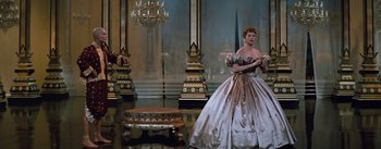 Movie still from “The King and I” (1956), directed by Walter Lang – A woman in a ball gown stands in front of chandeliers; Wide shot, Low angle