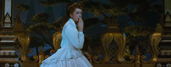 Movie still from “The King and I” (1956), directed by Walter Lang – A woman in a white dress standing next to a tree; Medium shot, Low angle