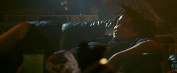 Movie still from “The King of Staten Island” (2020), directed by Judd Apatow – A man with dreadlocks sitting on top of a black couch; Medium shot, Over the shoulder angle