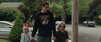 Movie still from “The King of Staten Island” (2020), directed by Judd Apatow – A man and a boy walking down a street holding hands; Medium shot, Low angle