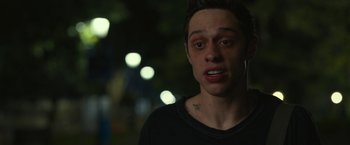 Movie still from “The King of Staten Island” (2020), directed by Judd Apatow – A young man with a black t - shirt is looking at the camera; Close Up shot, Over the shoulder angle