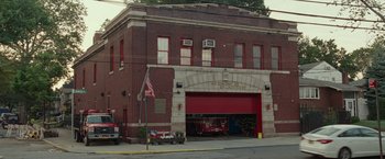 Movie still from “The King of Staten Island” (2020), directed by Judd Apatow – A fire station on a city street with an american flag on the side; Extreme Wide shot, High angle