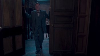 Movie still from “The King's Speech” (2010), directed by Tom Hooper – A man in a suit and bow tie walking through a room; Medium shot, Low angle
