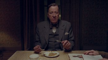 Movie still from “The King's Speech” (2010), directed by Tom Hooper – A man sitting at a table with a plate of food in front of him; Medium shot, Over the shoulder angle