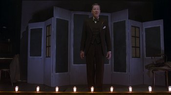 Movie still from “The King's Speech” (2010), directed by Tom Hooper – A man in a suit standing in front of candles; Medium shot, Low angle