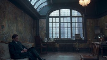 Movie still from “The King's Speech” (2010), directed by Tom Hooper – A person sitting on a couch in a room with a large window; Wide shot, High angle