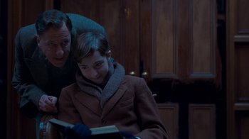 Movie still from “The King's Speech” (2010), directed by Tom Hooper – A man and a boy are reading a book together; Medium shot, Over the shoulder angle