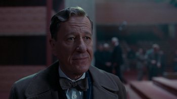Movie still from “The King's Speech” (2010), directed by Tom Hooper – An older man wearing a suit and bow tie; Close Up shot, Over the shoulder angle