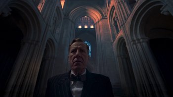 Movie still from “The King's Speech” (2010), directed by Tom Hooper – A man in a suit and bow tie in a cathedral; Medium shot, Low angle
