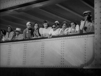 Movie still from “The Lady Eve” (1941), directed by Preston Sturges – A black and white photo of a group of people sitting on a train; Wide shot, High angle
