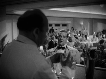 Movie still from “The Lady Eve” (1941), directed by Preston Sturges – A black - and - white photo of a man in a suit and bow tie; Medium shot, Over the shoulder angle