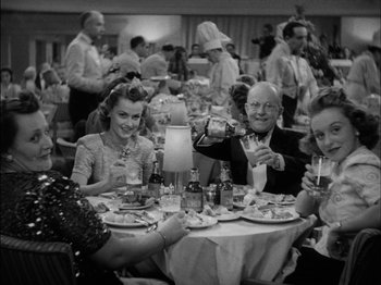 Movie still from “The Lady Eve” (1941), directed by Preston Sturges – A black and white photo of people sitting at a dinner table; Medium shot, High angle