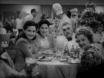 Movie still from “The Lady Eve” (1941), directed by Preston Sturges – A black and white photo of a group of people sitting at a table; Medium shot, High angle