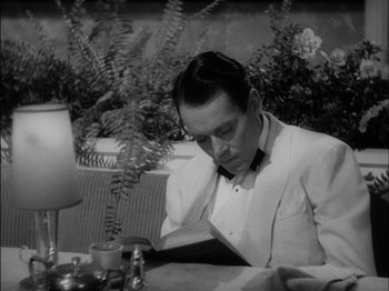 Movie still from “The Lady Eve” (1941), directed by Preston Sturges – A black and white photo of a man reading a book; Close Up shot, High angle