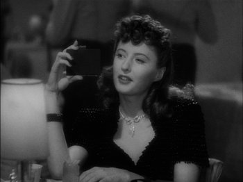 Movie still from “The Lady Eve” (1941), directed by Preston Sturges – A black and white photo of a woman holding a camera; Close Up shot, Over the shoulder angle