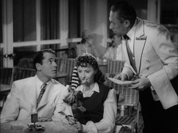 Movie still from “The Lady Eve” (1941), directed by Preston Sturges – An old photo of two people sitting at a table with a waiter; Medium shot, High angle