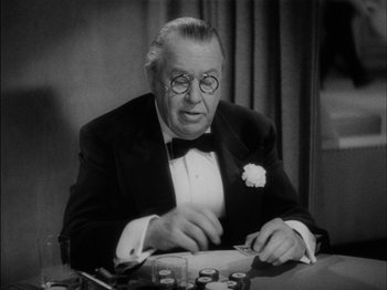 Movie still from “The Lady Eve” (1941), directed by Preston Sturges – An older man sitting at a table in front of a bunch of bottles; Close Up shot, High angle