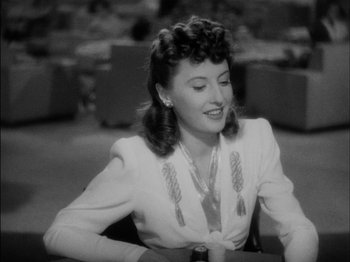 Movie still from “The Lady Eve” (1941), directed by Preston Sturges – An old black and white photo of a woman sitting at a table; Close Up shot, Over the shoulder angle