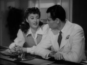 Movie still from “The Lady Eve” (1941), directed by Preston Sturges – A man and a woman sitting at a table with a glass; Medium shot, Over the shoulder angle